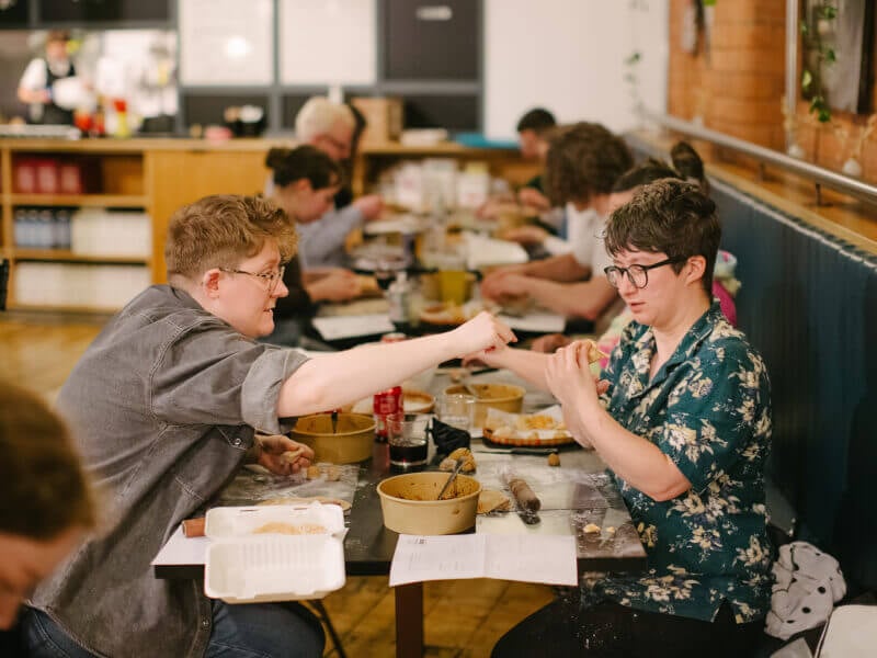 A couple helping each other cook at a couples cooking class