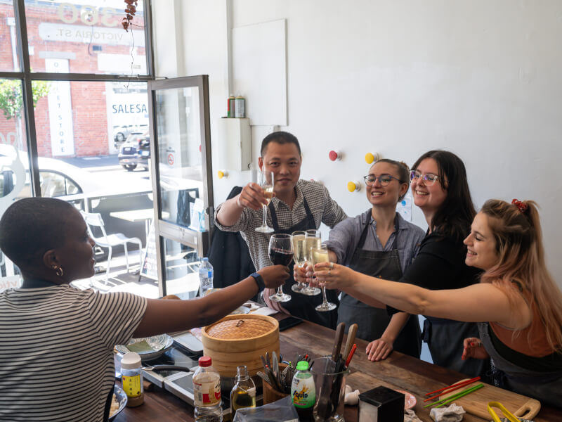 Women clink glasses at a cooking class for hens parties