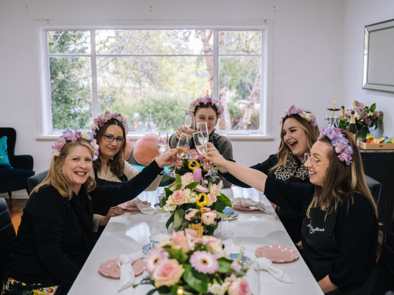 A bride-to-be and her friends cheers with champagne at a flower arranging class