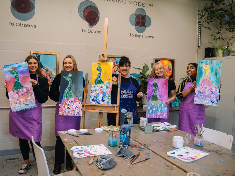 Four friends pose with their finished artworks at a paint and sip hens party