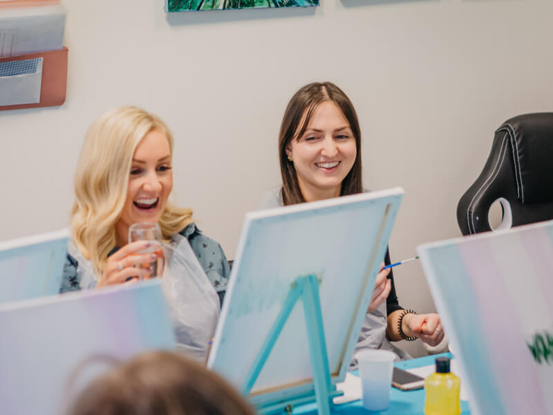 Woman laughing with wine and art
