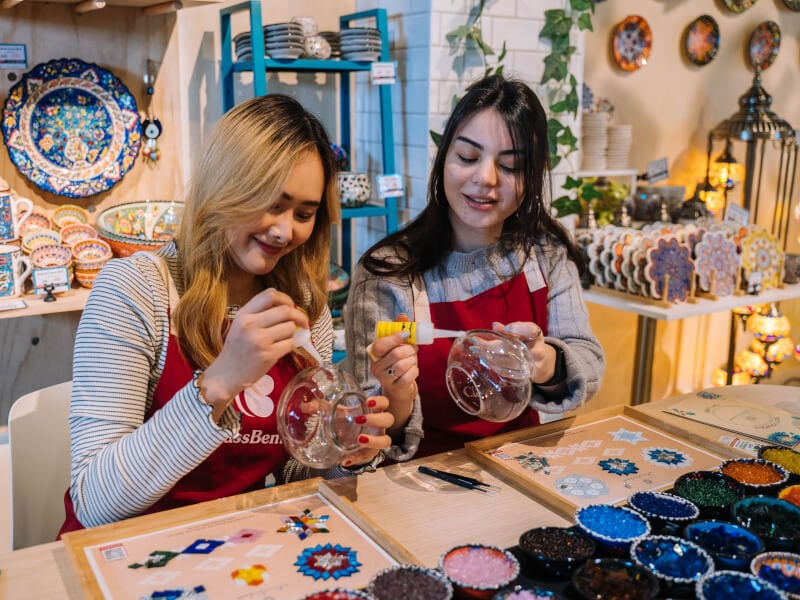 Two friends smiling as they make Turkish mosaic lamps at a bachelorette party
