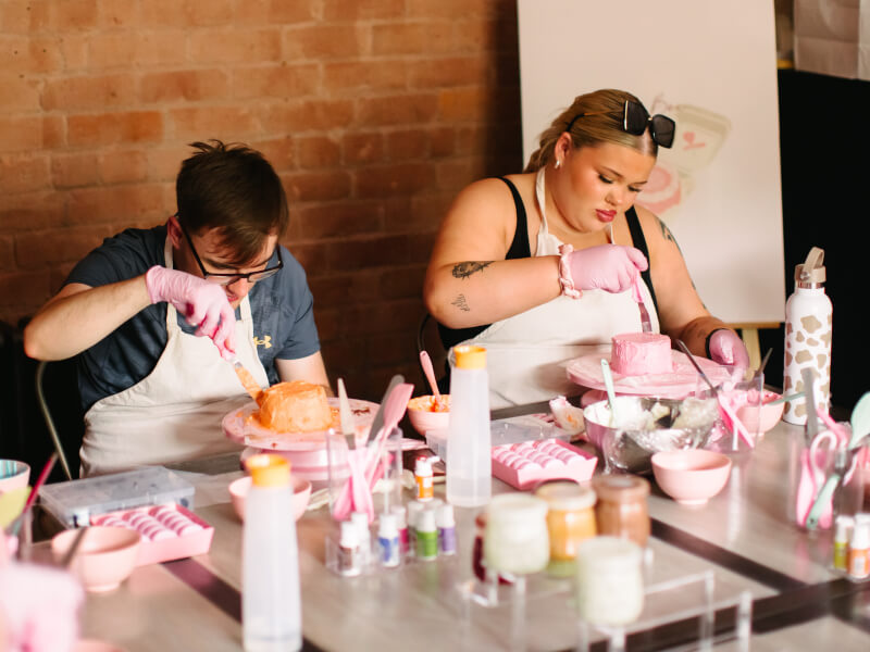 Two friends decorating cakes together