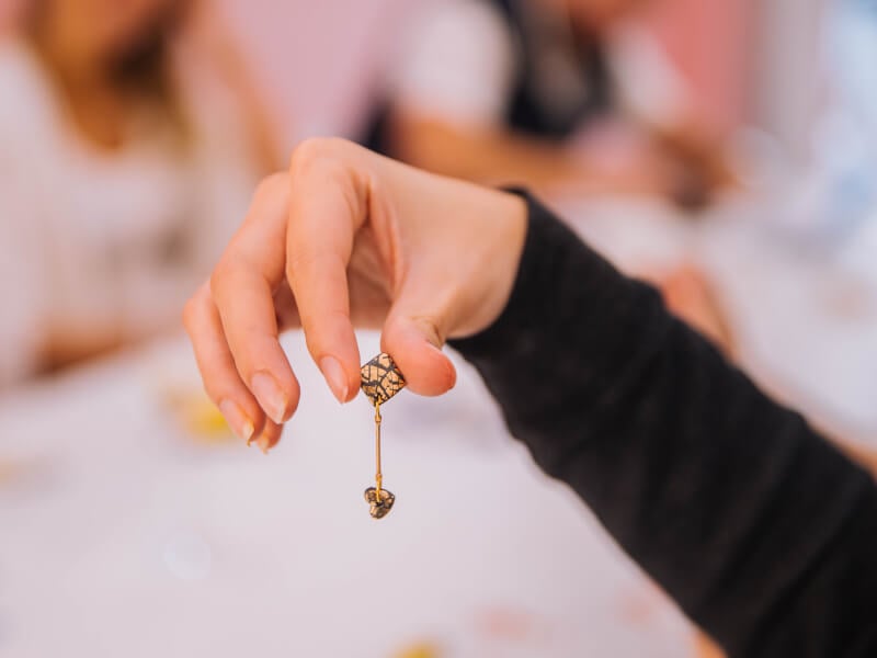 A hand holding up dangly earrings