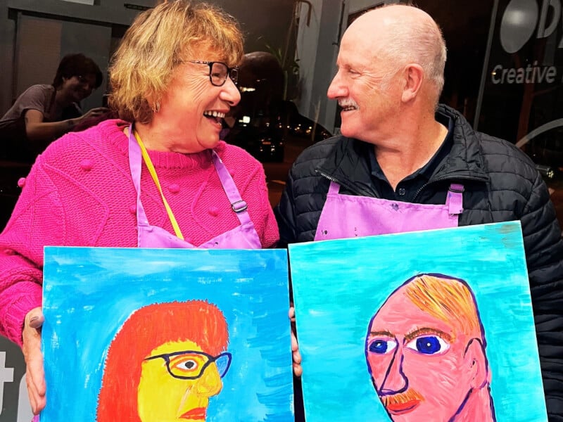 A husband and wife holding their portraits of each other