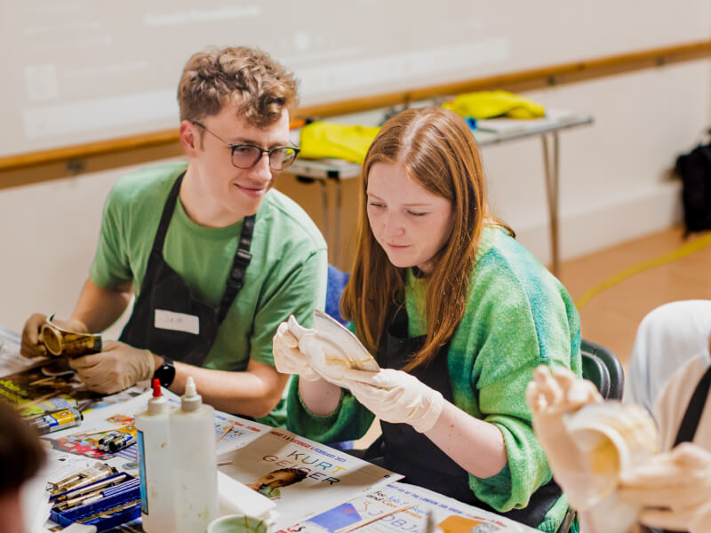 Brother and sister helping each other at family-friendly pottery class