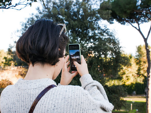 A woman takes a photo of nature with her iphone