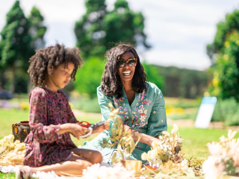 Mother and daughter making dried flower arrangements outside