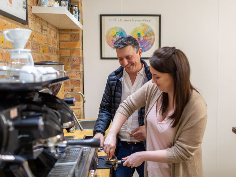 Father watching daughter make coffee