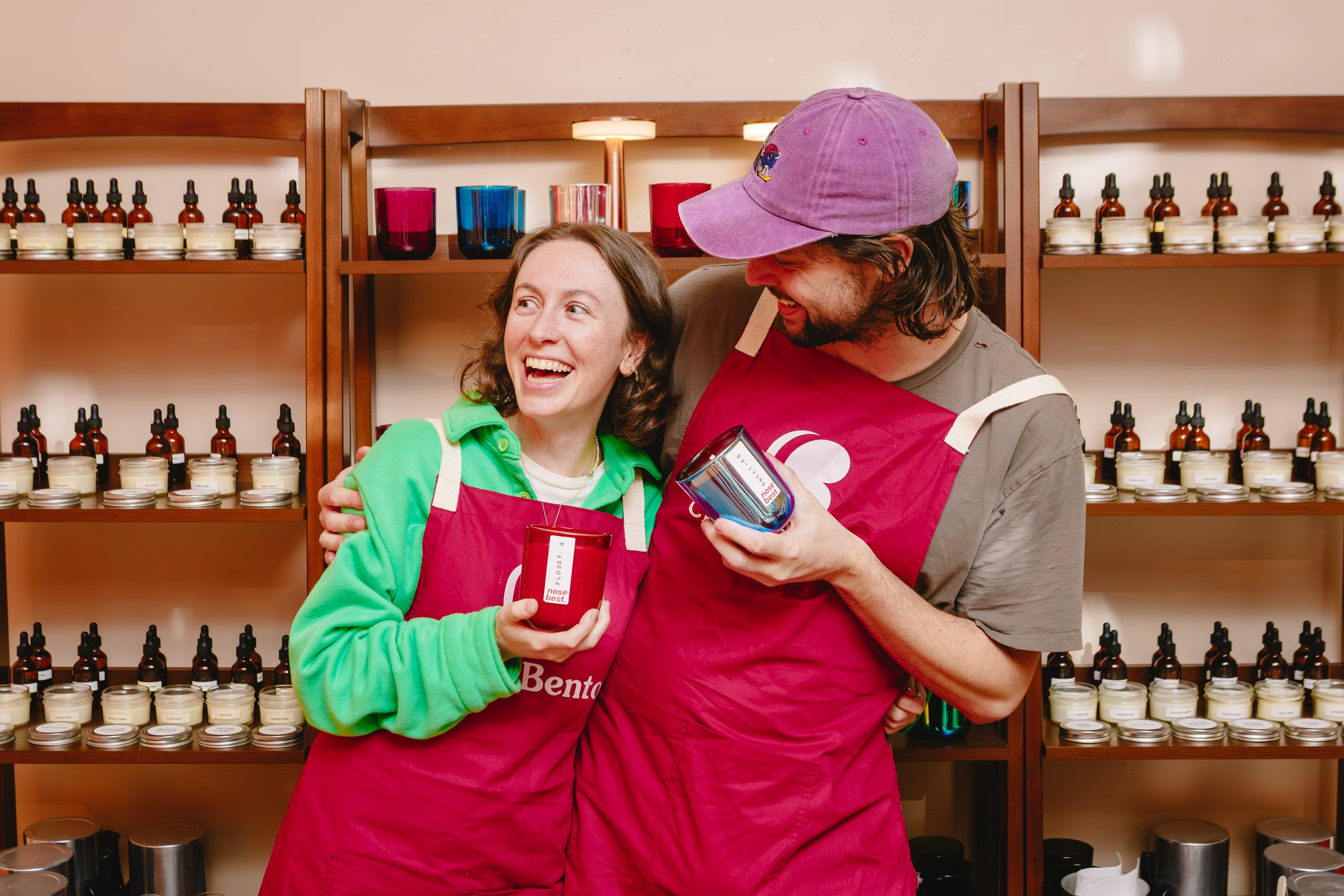 A laughing couple embrace while holding handmade candles