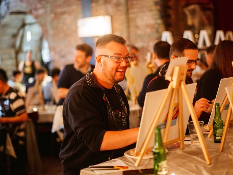 A man laughing at a paint and sip event