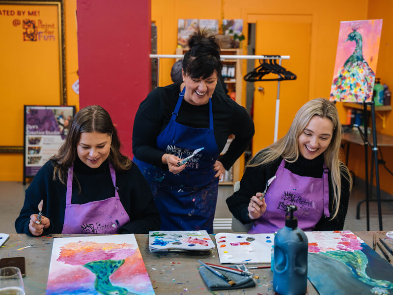 Art students laughing with their teacher at painting class
