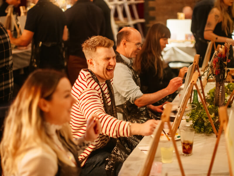 A man laughing heartily at a paint and sip event