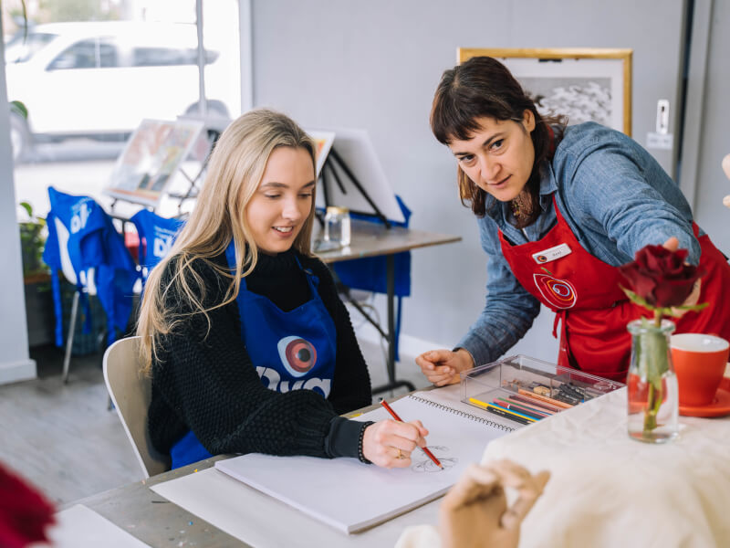 A student gets life drawing tips from her teacher