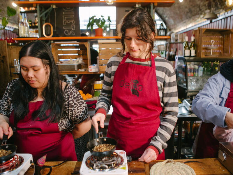 Two colleagues learning to roast coffee in a pan at a Melbourne barista class