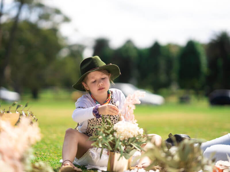 A little girl sits in the sunshine flower arranging
