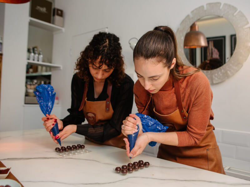 Two women make chocolate truffles
