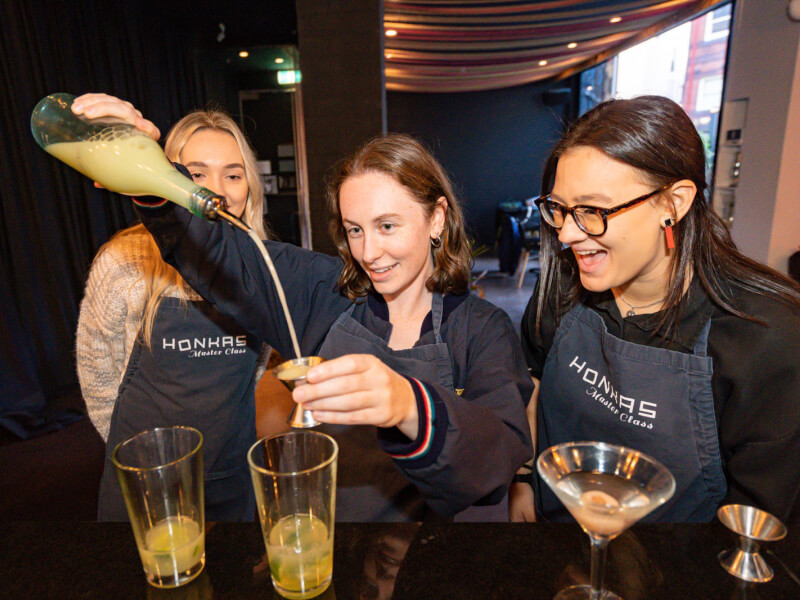Three women making cocktails at a workshop birthday party