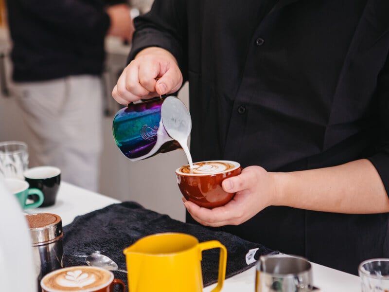 A man pours milk and makes latte art at a barista course