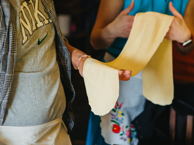 Two people stretching out pasta dough at a Sydney couples cooking class