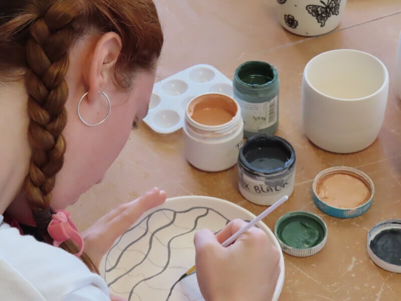 A woman adds patterns to her ceramics