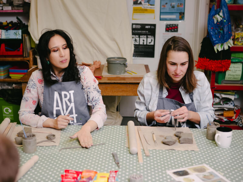 Two women making coffee cups at a pottery class