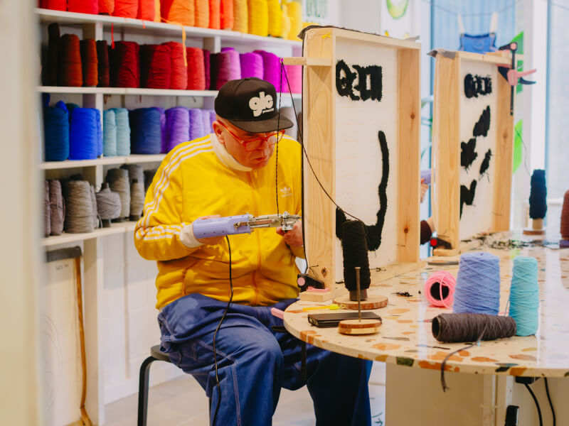 A man focused on tufting his own rug