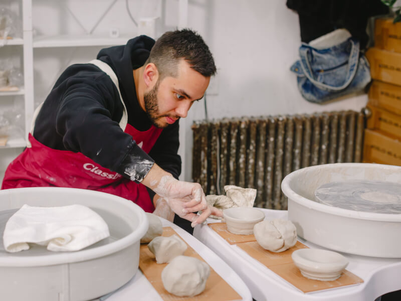 A man focused at the wheel during a pottery class