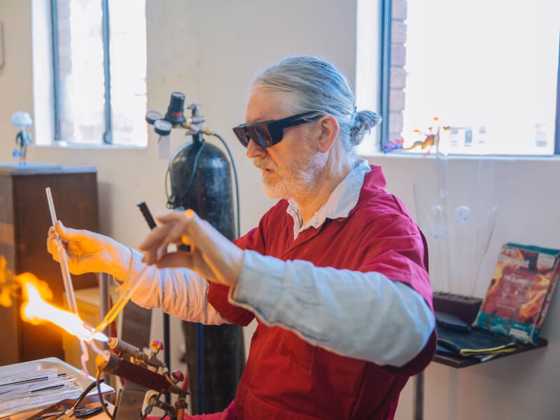A man melts glass in a glassblowing experience