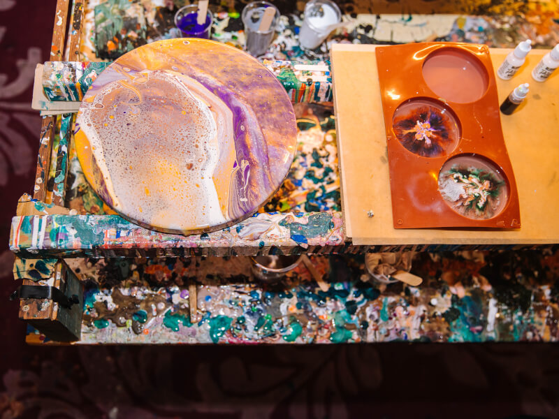 Vibrant and colourful fluid art on paint splattered work space