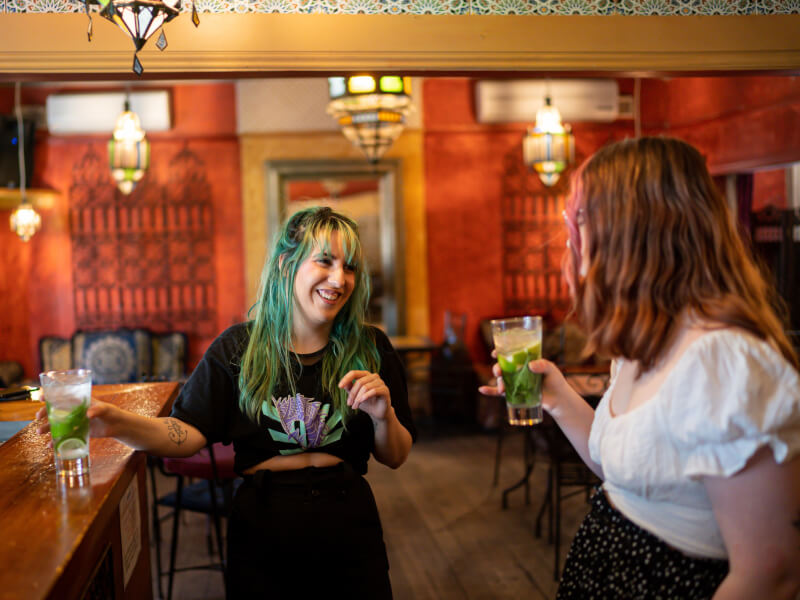 Two friends laughing and holding mojito's at a cocktail class for hens parties