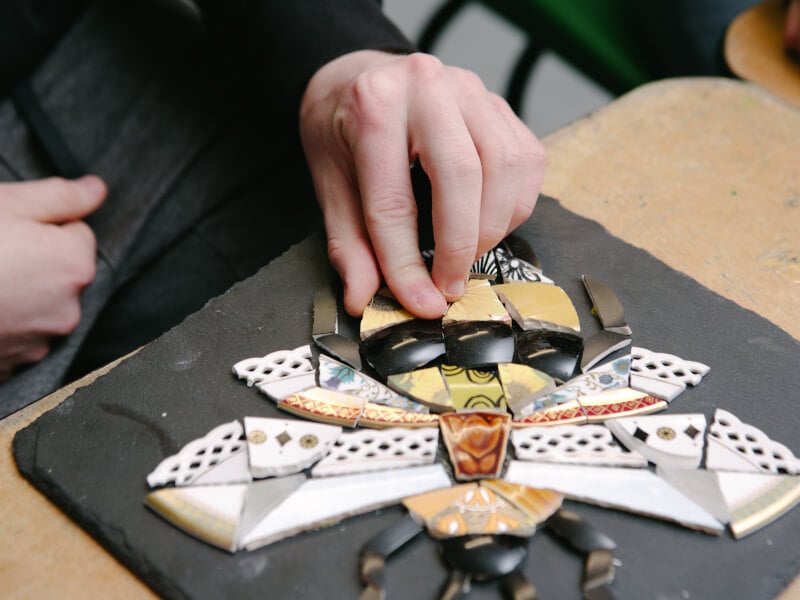 A hand adds the finishing piece to a bee mosaic art