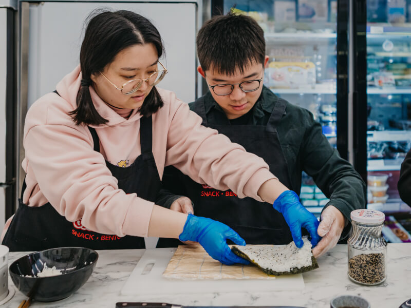 A mother and son make sushi at a cooking class