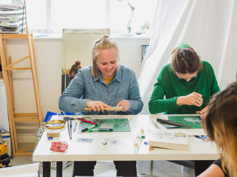 Mother and daughter smiling as they make jewellery together on Mother's Day
