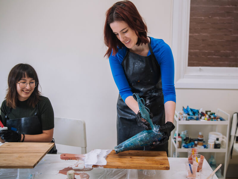 A woman putting resin on her cheeseboard
