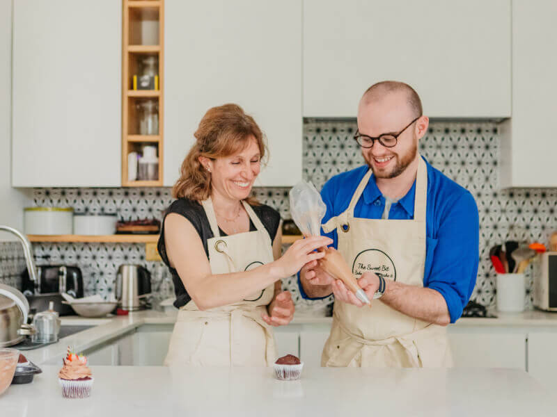A mother and son decorate cupcakes