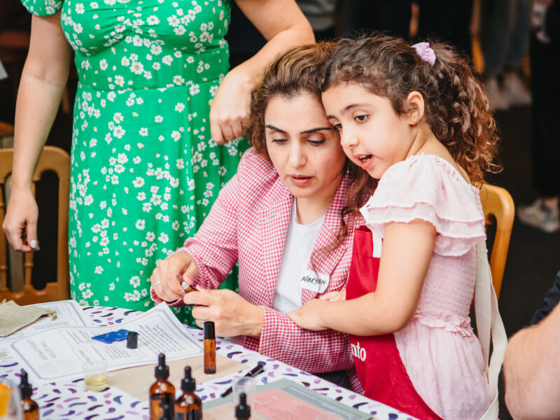 A mother and her young daughter sample essential oils at a skincare class