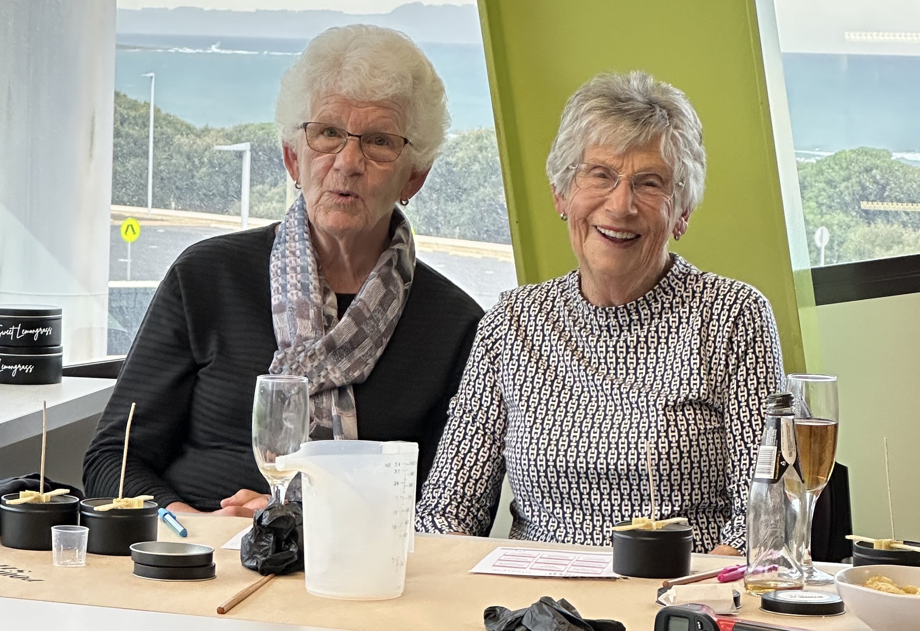 Two older women smiling at a candle making class