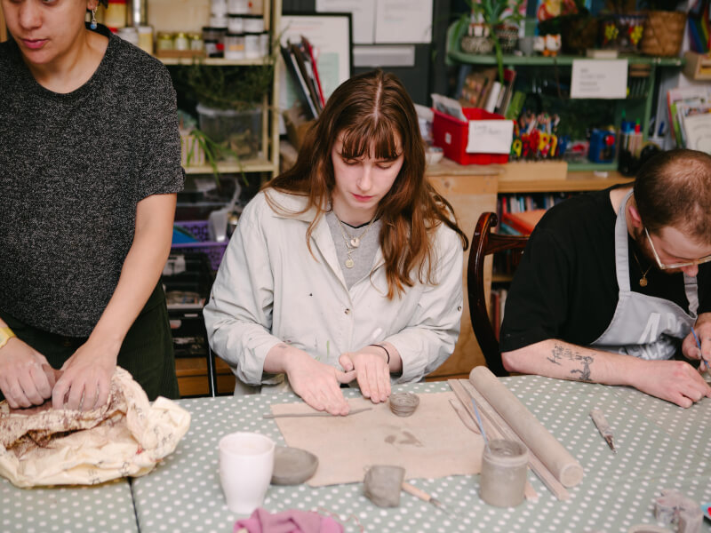 A woman focused on making a mug out of clay