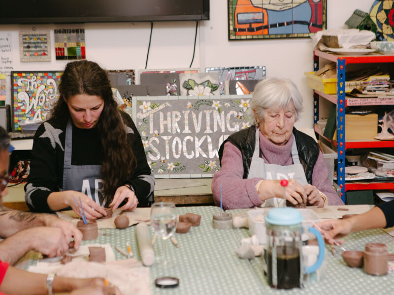 A mother and her daughter smiling at a pottery class for Mother's Day