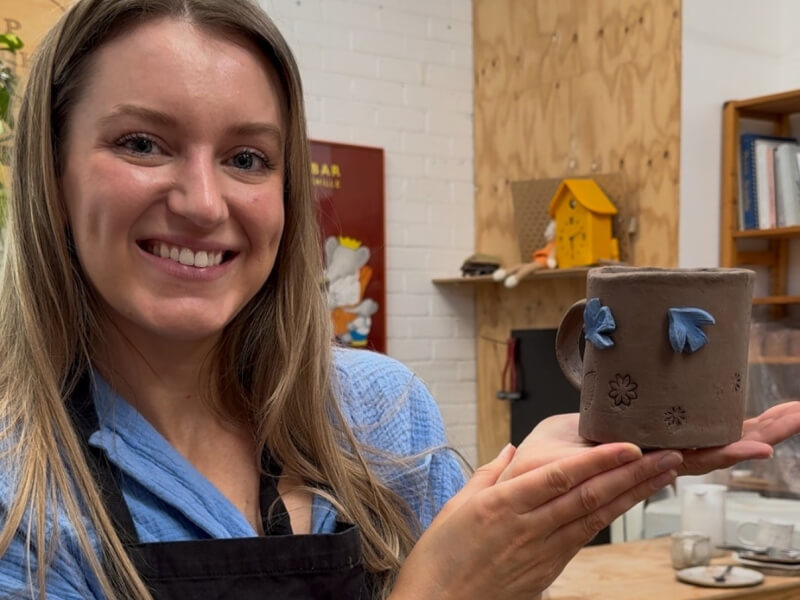 A woman holds up her handmade mug