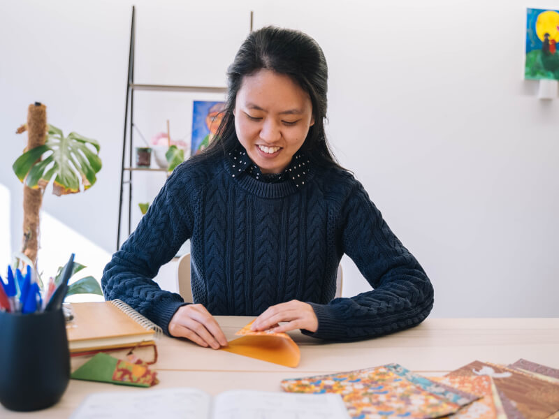A woman smiles while enjoying origami in Melbourne