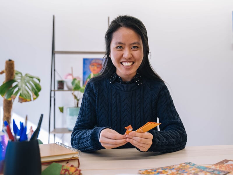 A woman holding a paper crane at an origami class