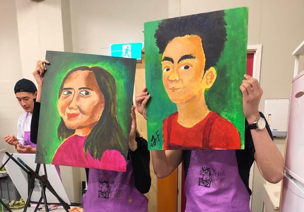 Boyfriend and girlfriend posing with their portraits of each other