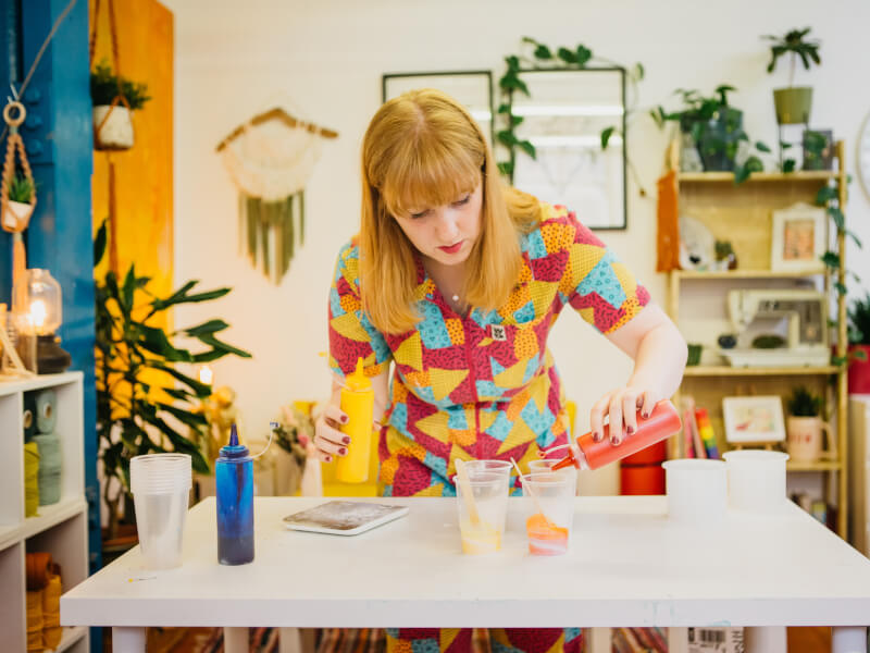 An art teacher pours paint into cups