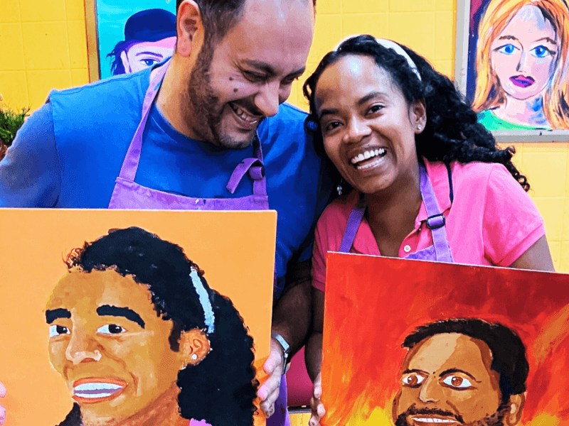 A couple laughing with paintings of each other