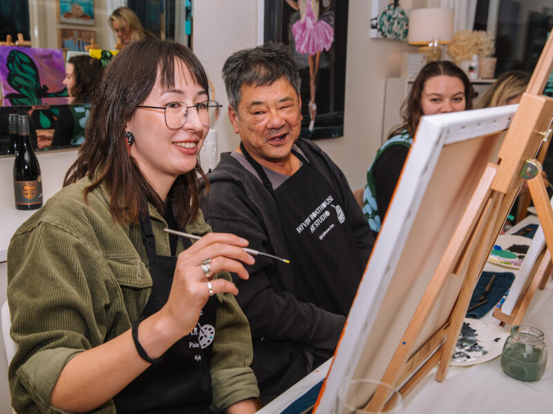 An older man laughing at a paint and sip class