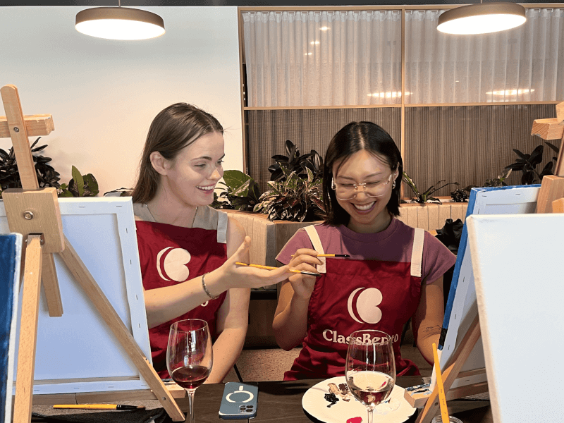 Two colleagues paint and sip