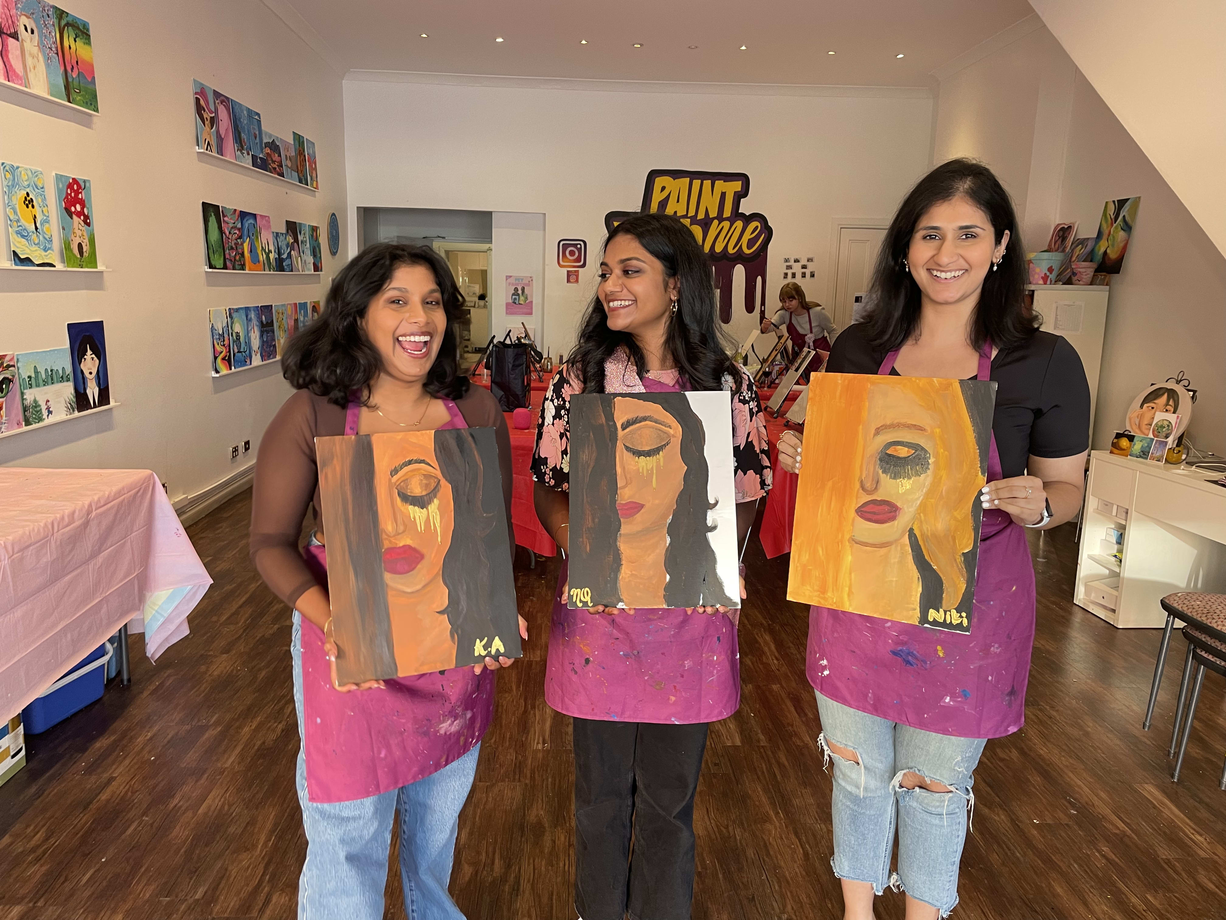 Three friends show their completed artworks at the Paint With Me studio