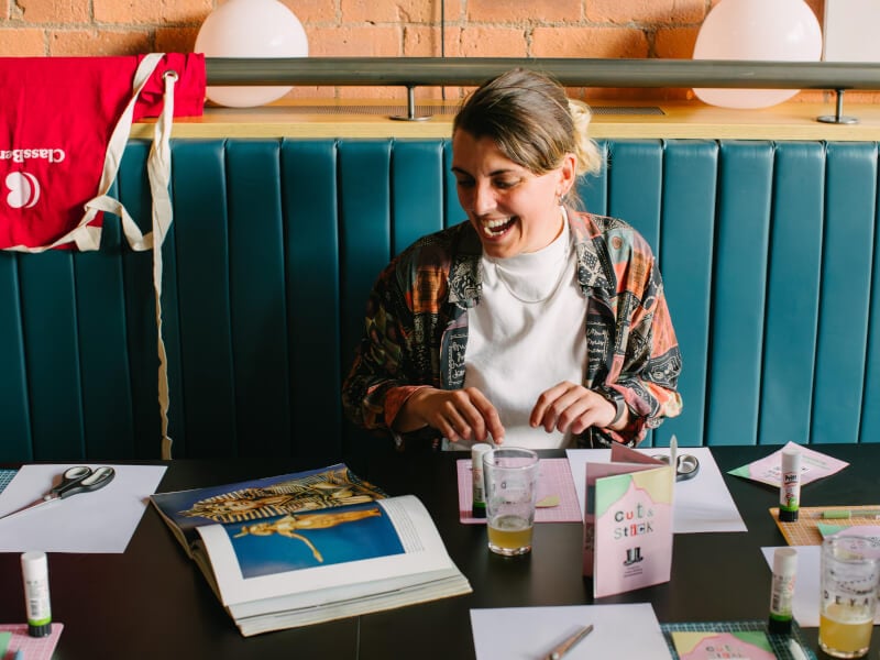 A happy woman smiling at a paper craft and ink workshop